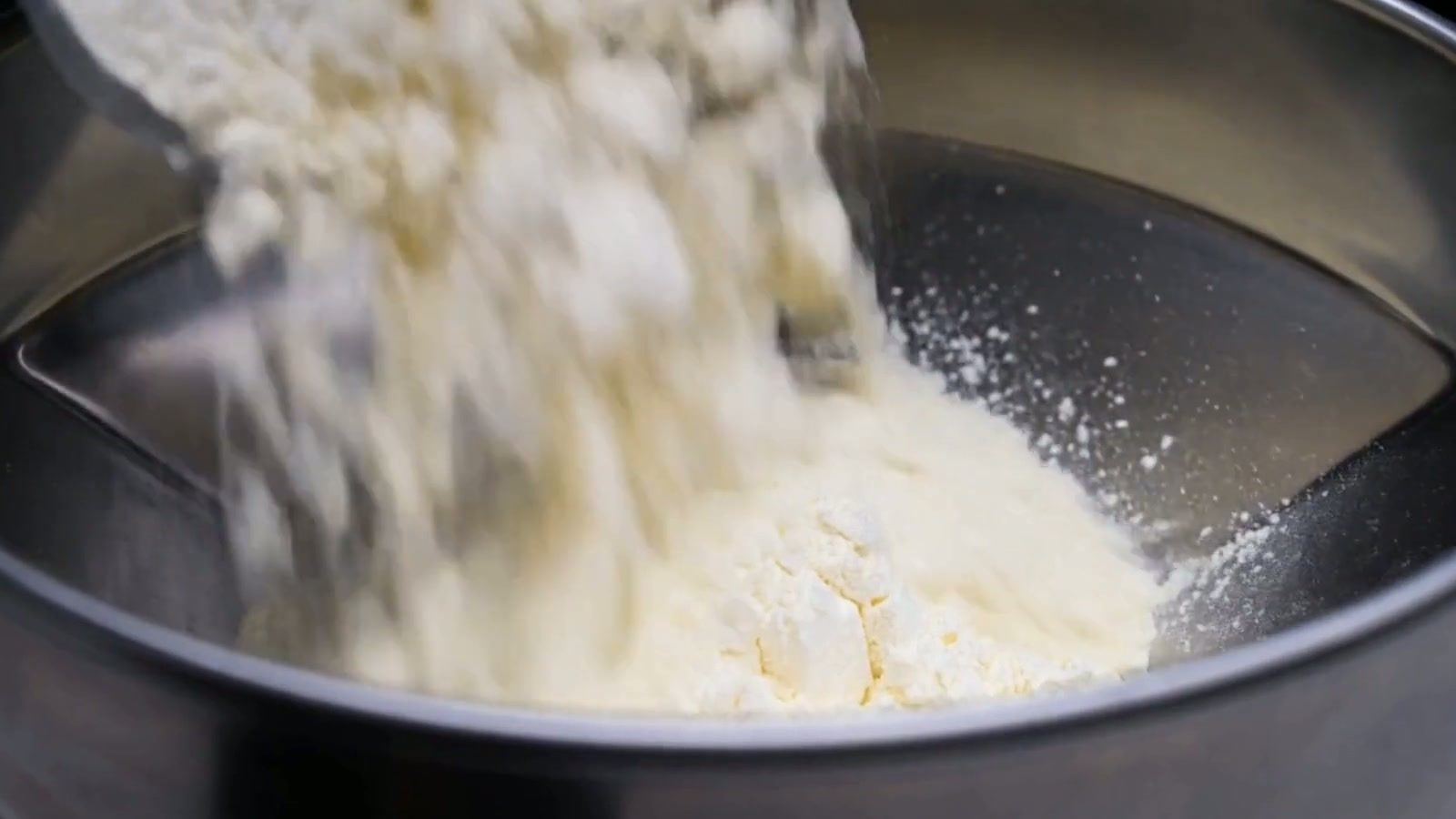 Close-up of protein powder pouring into a stainless steel vessel